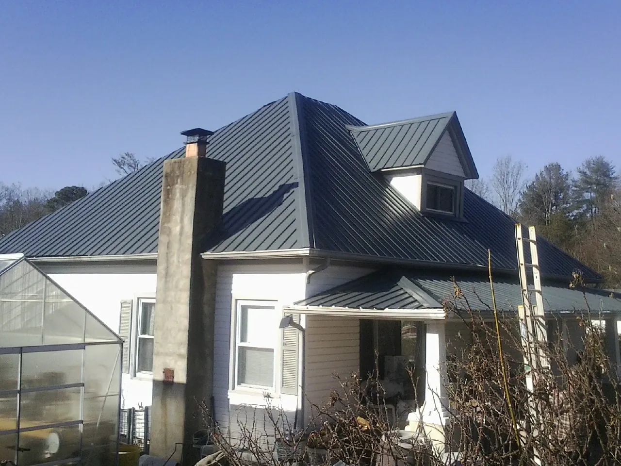 Dark blue standing seam metal roof on a white farmhouse with dormer — Slate & Tile Roof Repair by Roofing Brothers in Maytown