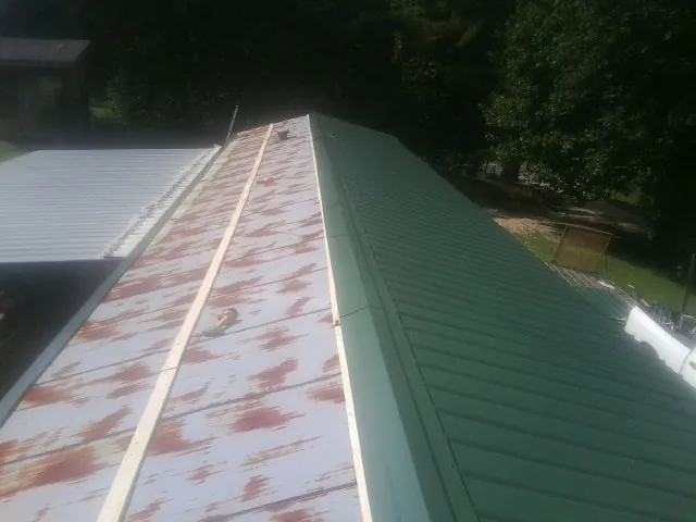 Old rusted panels beside newly installed green metal roofing — Wind Damage Roof Repair by Roofing Brothers in Maytown