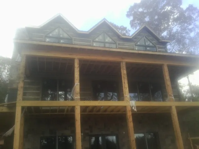 Dormers and porch framing on a large log home under construction — Roof Coating work by our crew in Maytown