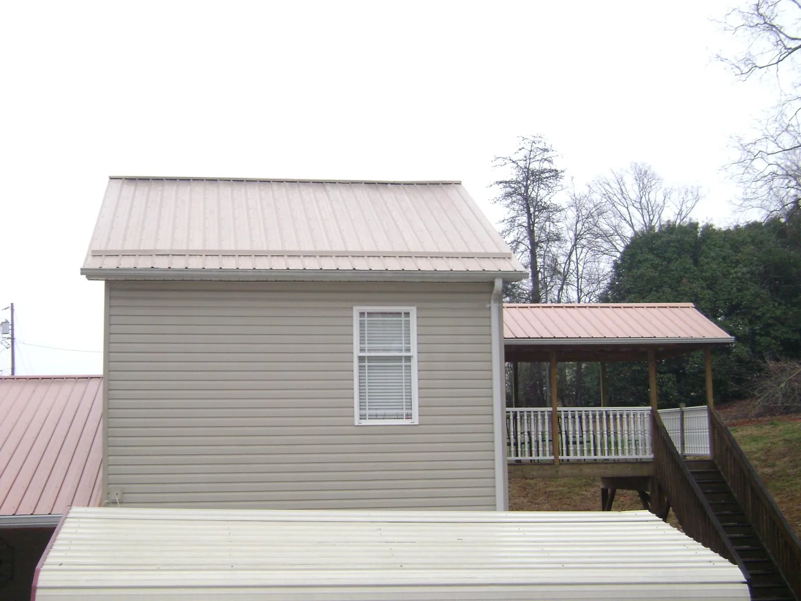 Tan metal roofs on a two story addition and attached porch, from a Roof Replacement job in Maytown